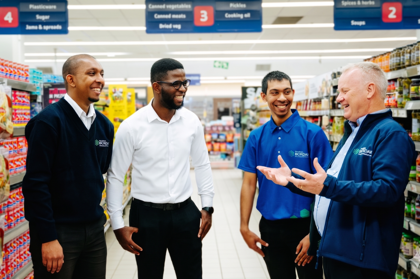 Bordax team members in conversation with a store manager in a supermarket aisle